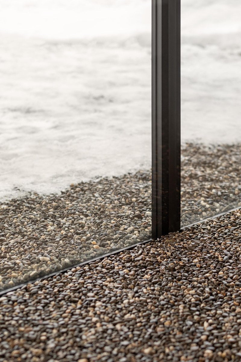 Detail of glazing profile meeting polished aggregate terrazzo floor with exposed stone