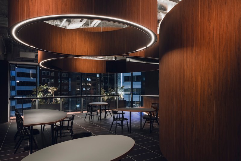 Evening view of dining area showing circular LED pendants and city lights through floor-to-ceiling glazing