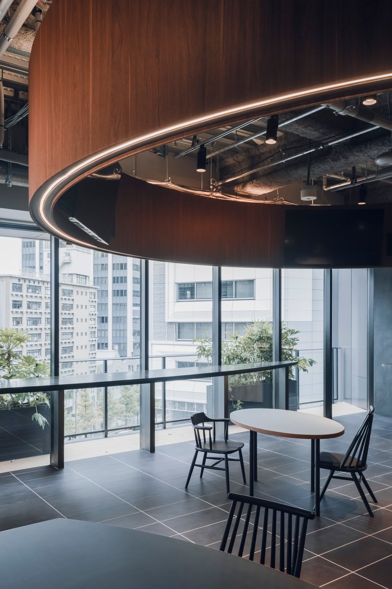 Detail of the sweeping wood canopy edge with concealed linear lighting beside full-height glazing and terrace planters
