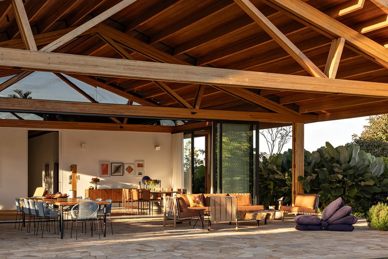 Covered outdoor terrace with stone paving and exposed timber trusses opening to lush tropical planting