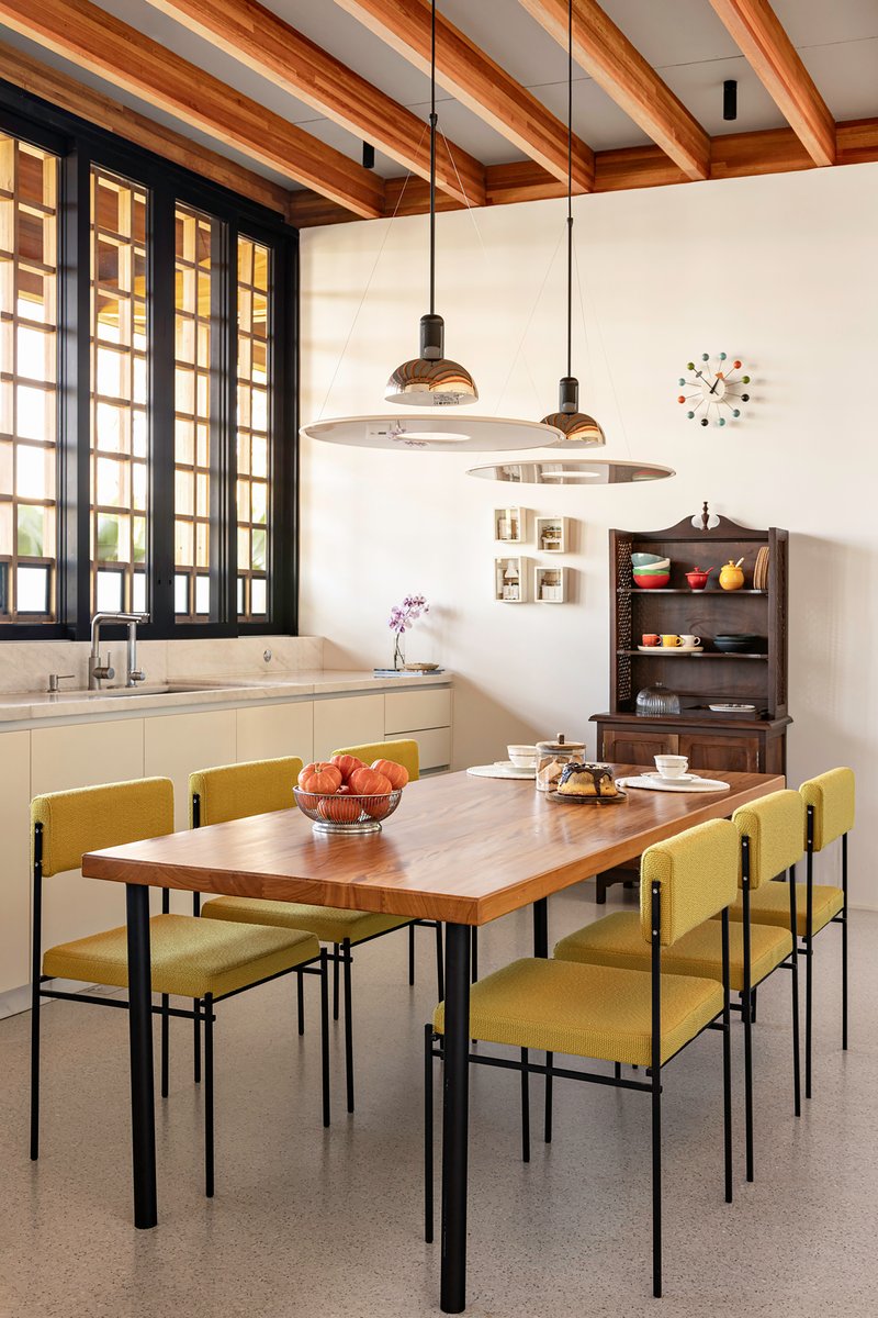 Dining area with timber table, olive upholstered chairs and dark gridded windows under exposed beam ceiling