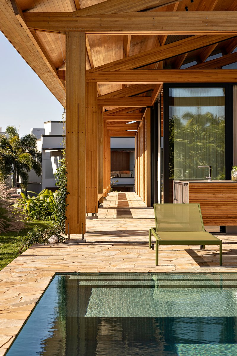 Exterior terrace with small pool, timber structure and green lounge chair overlooking lawn and palms