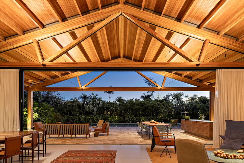 Exposed timber truss ceiling above the open living area looking out to the garden at dusk