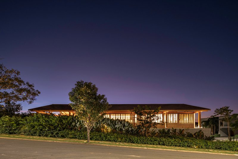Street view of the illuminated glazed facade and low-pitched roof at night