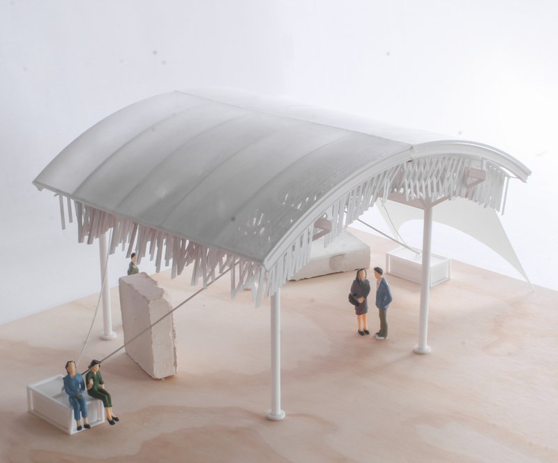 Physical model of the curved roof canopy with white columns, icicle-like elements, and miniature figures on a base