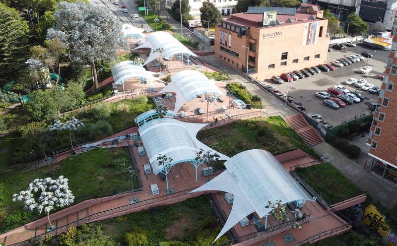 Aerial view of the serpentine canopy system with planted terraces between curved pavilion roofs and adjacent parking