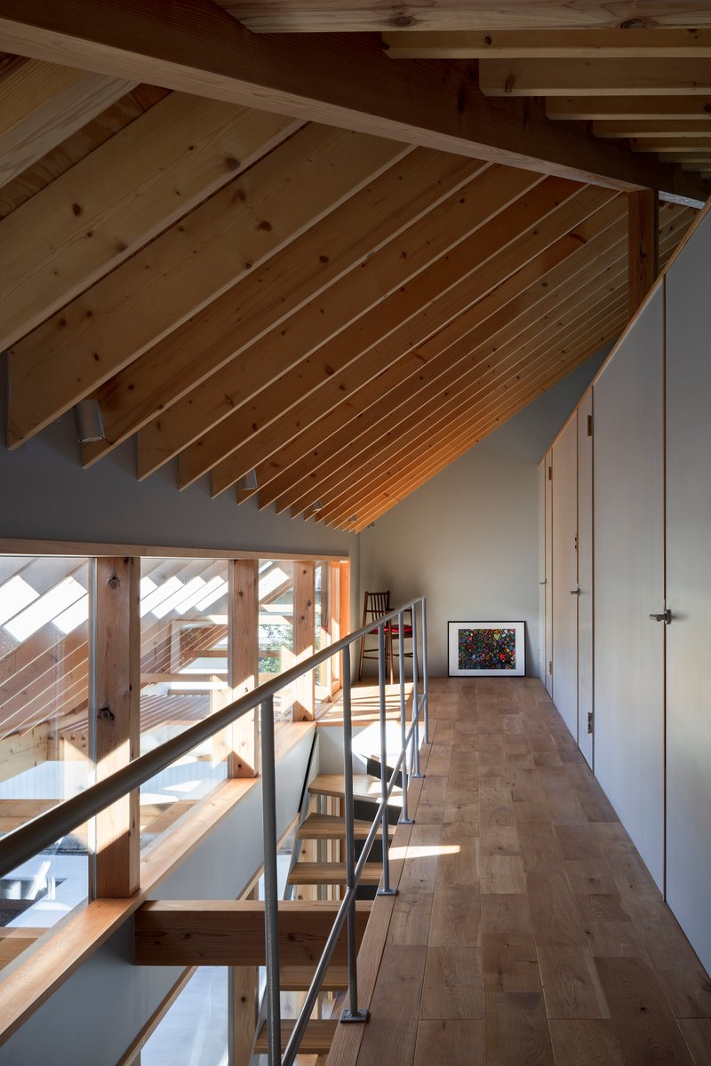 Mezzanine corridor with sloped timber ceiling and steel handrail along the open edge in morning light