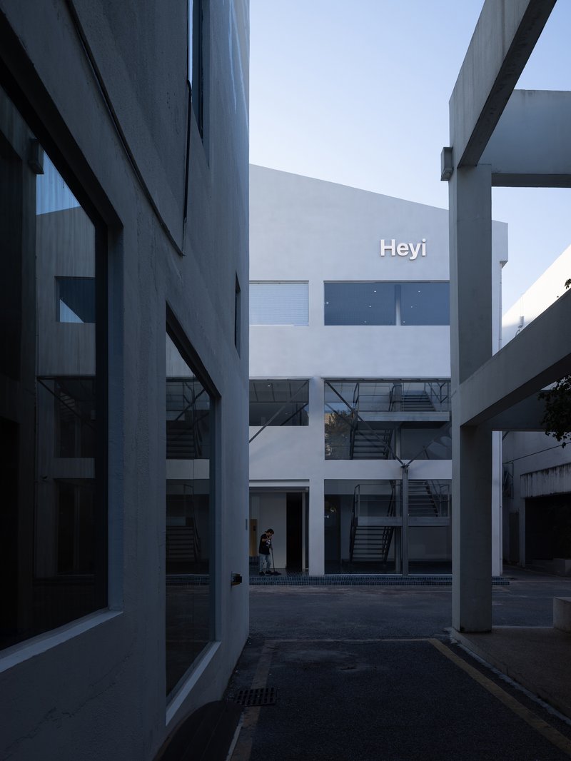 Courtyard view between white volumes with external steel staircases and bridges connecting upper floors