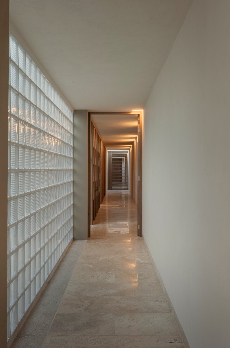 Long corridor with glass block wall filtering daylight along one side to timber doorways