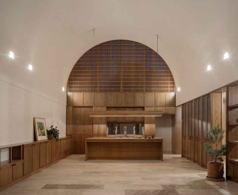 Kitchen island under a vaulted ceiling with timber slat arch and recessed wall lighting