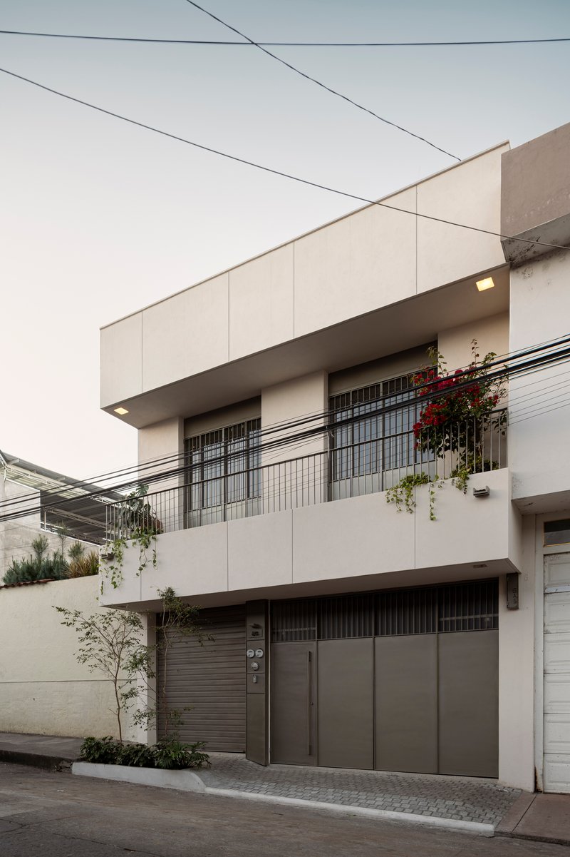 Three-story street elevation showing glass block windows, planted balconies, and overhead utility wires
