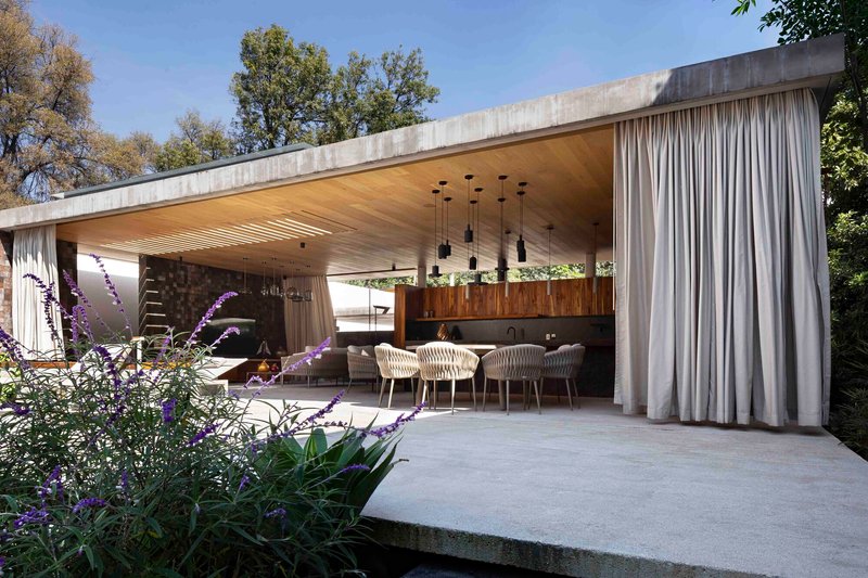 The pavilion seen from the garden with linen curtains framing the dining area