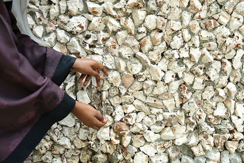 Hands touching a wall surface composed of white crushed coral or oyster shell aggregate