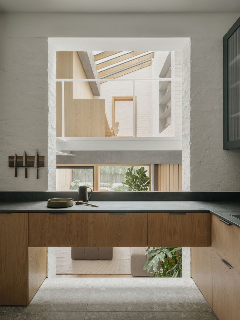 Kitchen island with dark countertop framing views through a vertical opening to the upper level