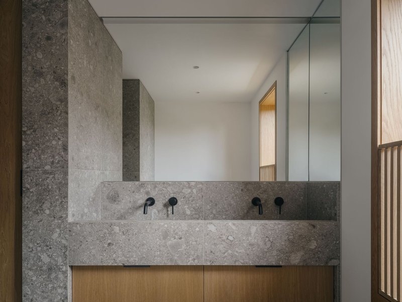 Double vanity with grey limestone and timber cabinetry beneath a full-width mirror in a bathroom