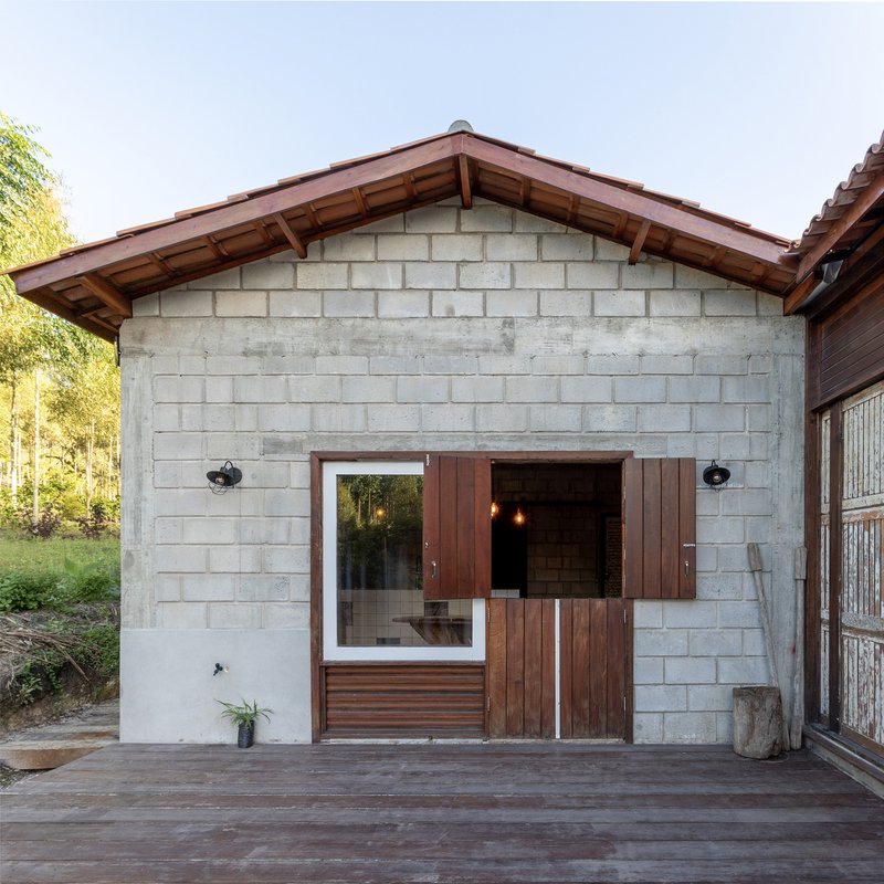 Exterior gable facade with concrete block walls, timber shutters and exposed rafters under overcast sky