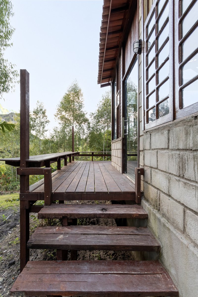 Timber stairs descending from elevated deck porch beside concrete block base and gridded window facade