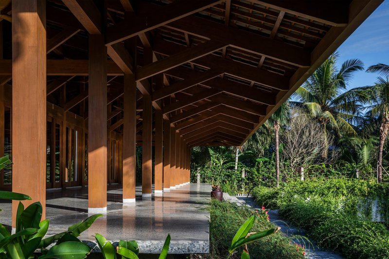 Covered terrace with timber structure and polished concrete floor overlooking palm trees