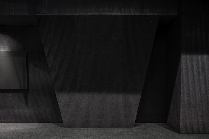 Interior corner showing a tapered dark column against ribbed wall surfaces in low light