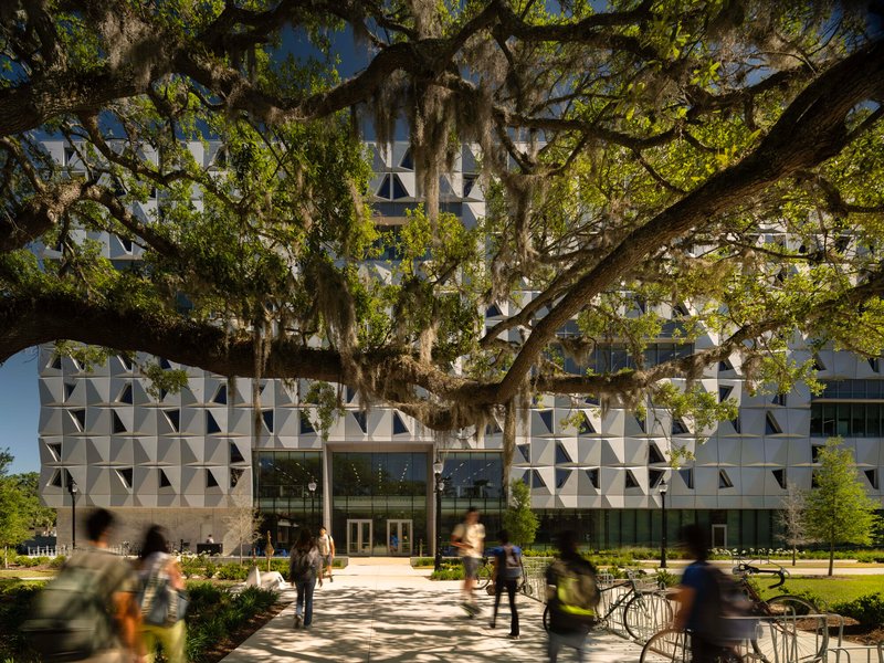 Entry facade with triangular relief panels framed by sprawling oak tree branches draped with Spanish moss