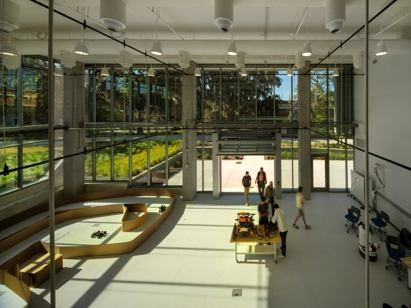 Double-height lobby with full-height glazing overlooking a planted courtyard as students gather inside