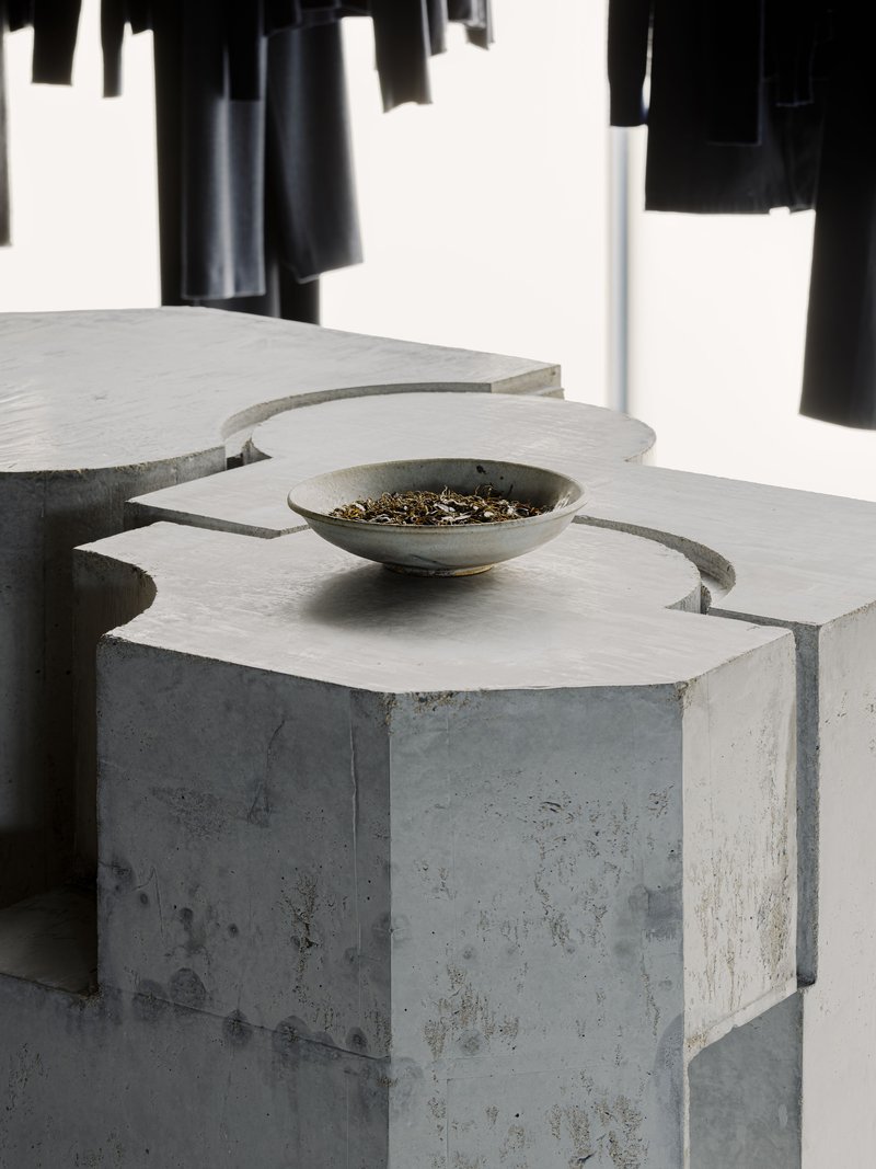 Close-up of a ceramic bowl resting on an interlocking concrete volume with chamfered edges