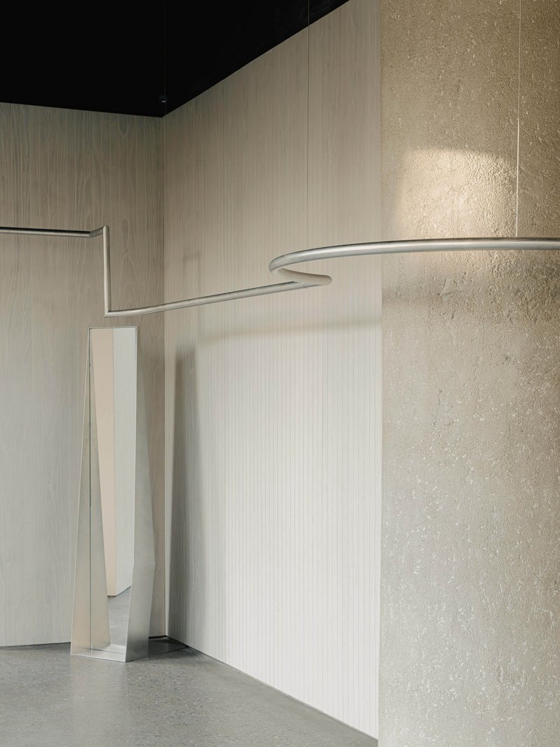 Narrow vertical slot in a pale paneled wall adjacent to a textured plaster column