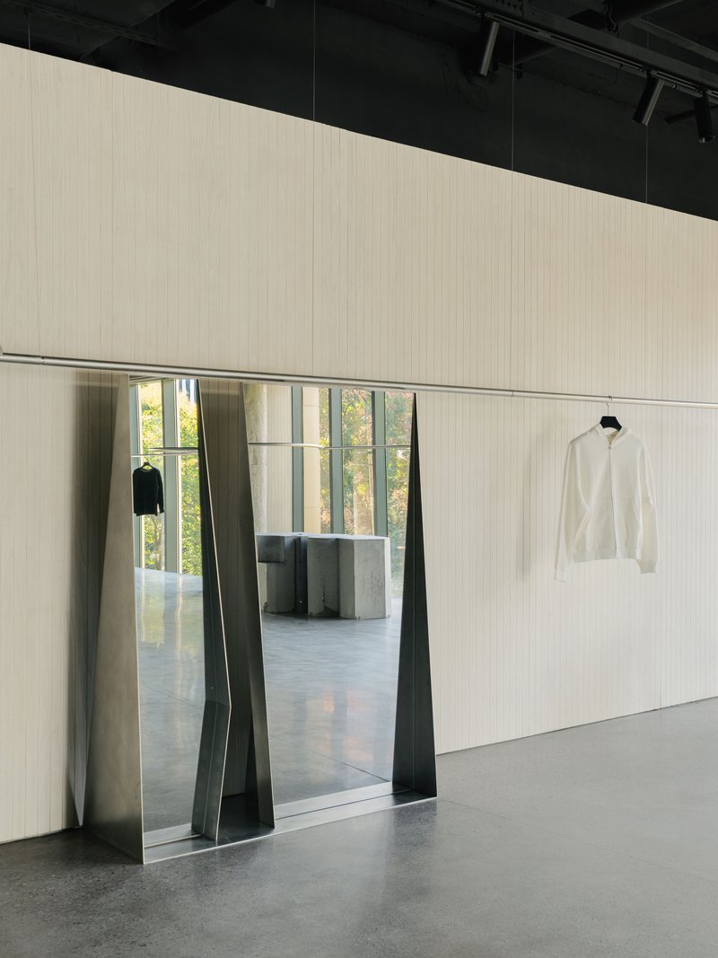 Trapezoidal doorway with folded metal jambs framing view into adjacent room with concrete columns