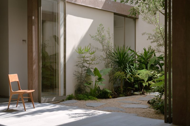 Interior courtyard with planted beds of tropical vegetation visible through sliding glass doors