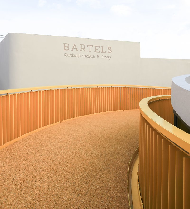 Curving service counter with vertical timber battens and cork flooring beneath signage wall