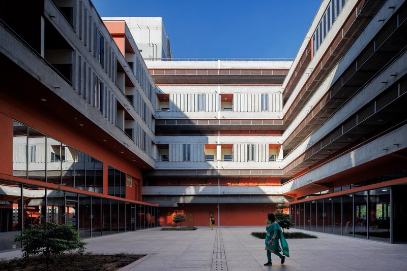 Inner courtyard at ground level with a figure walking past the glazed lobby