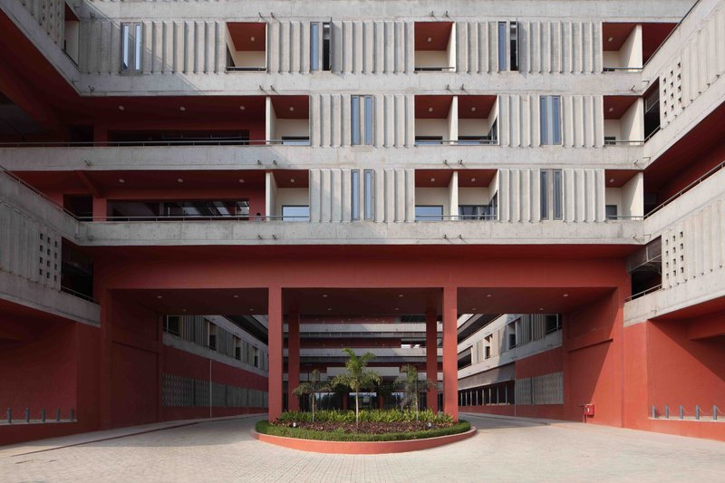 Red entry porte cochère with concrete columns and a circular planter