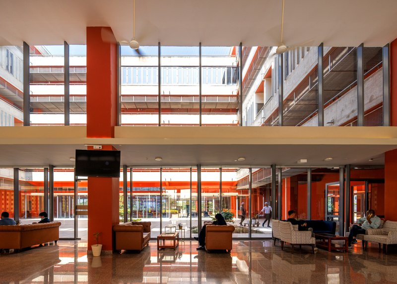 Double-height lobby with terrazzo floor, sofas and a view through to the courtyard