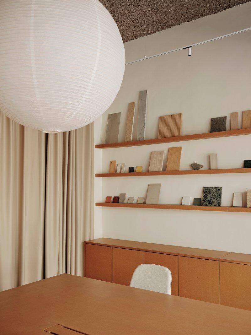 Timber shelving with material samples above a low cabinet and table beneath a spherical paper lantern