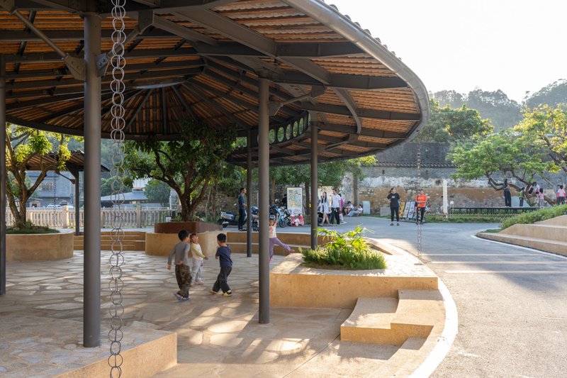 View beneath the pavilion showing stepped seating platforms and a rain chain suspended from the bamboo ceiling structure