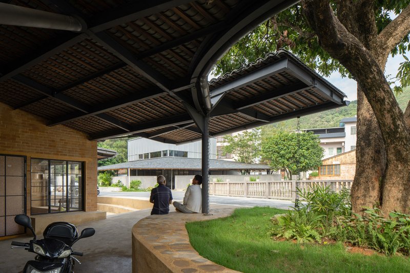 Covered porch with timber lattice ceiling and steel columns framing a curved seating wall and tree