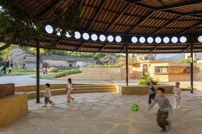 This architectural image showcases a modern pavilion in a village setting, designed as a community s