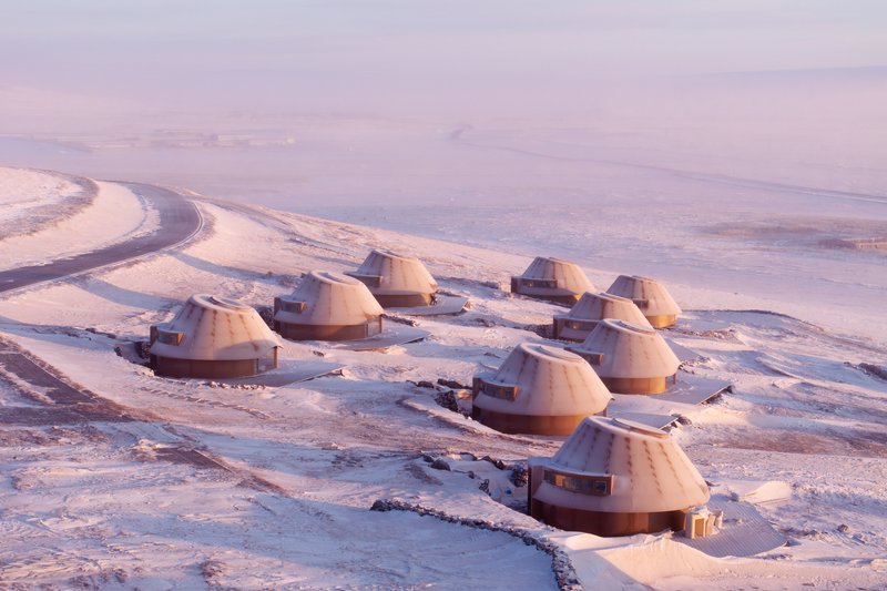 Aerial view of dome-roofed units connected by pathways across a snow-covered landscape at dusk