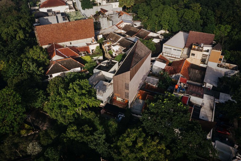 Aerial view of densely packed terracotta tile roofs and courtyards surrounded by mature trees