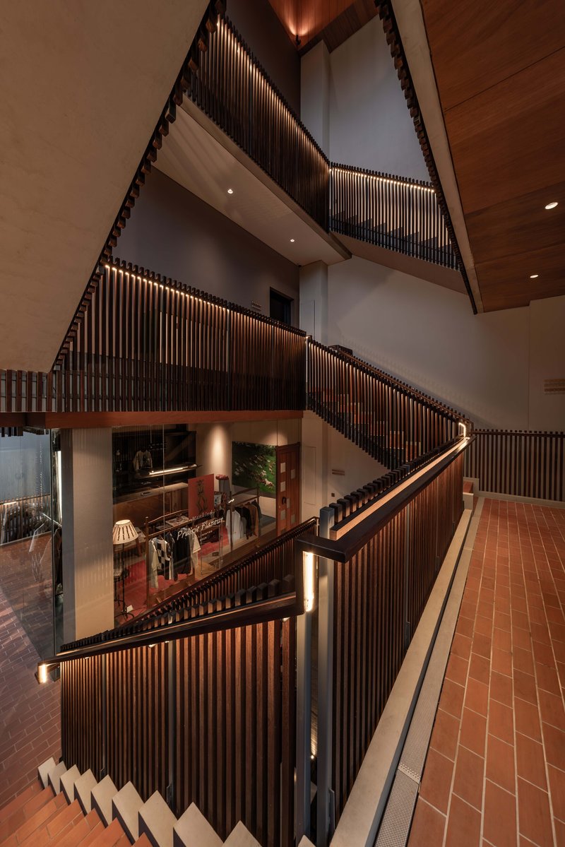 Stacked staircases with timber slat railings and backlit handrails in a multilevel interior atrium