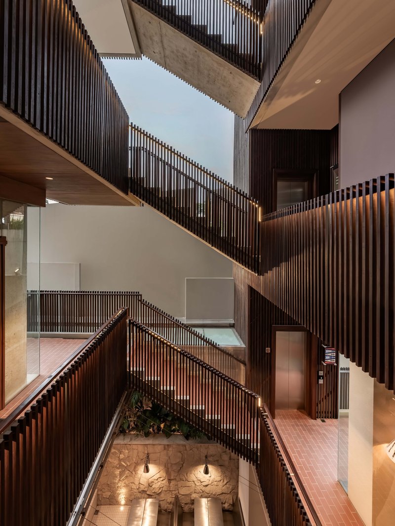 Multilevel atrium with zigzagging stairs, timber slat screens and a skylight overhead