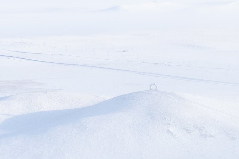 Distant horizon view of a tiny circular structure sitting on a low rise in the snow