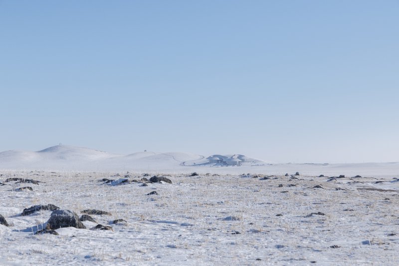 Wide view of the bare grassland horizon with low volcanic hills in the distance