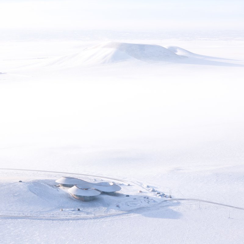 Distant aerial of the visitor center sitting in the snow with the extinct volcano cone behind