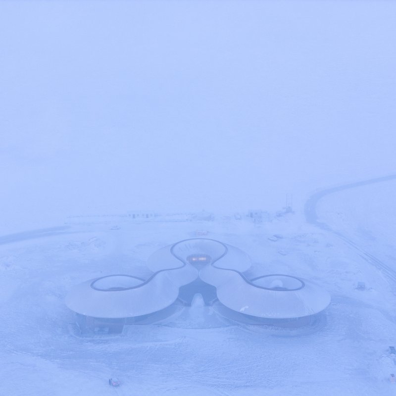 Top-down view of the three-lobed roof in heavy snow and mist
