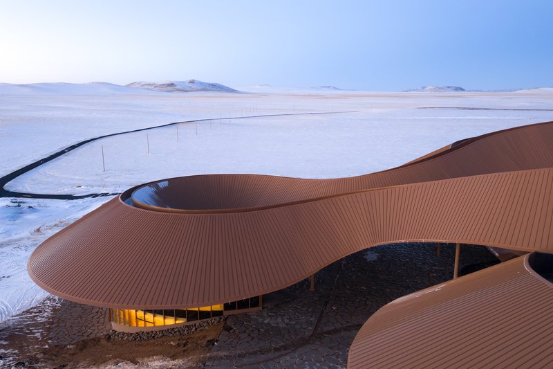 Long view of the fluid roof curves stretching across the white landscape