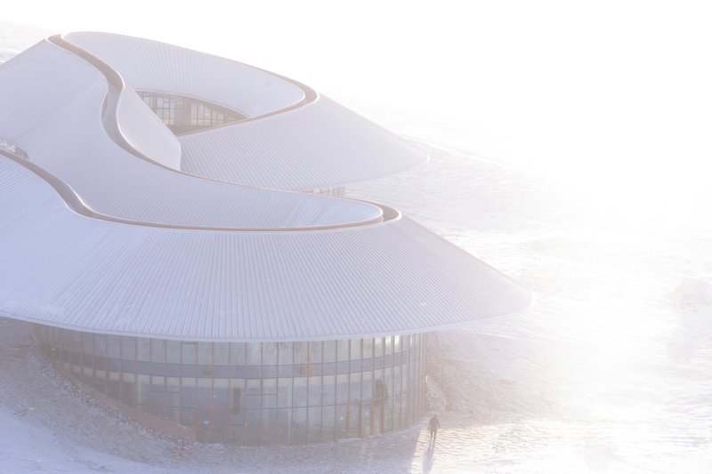 Front view through mist showing the glazed ground floor under the curving roof