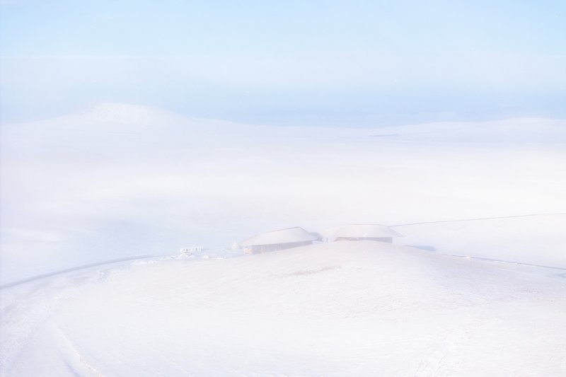 Almost-monochrome view of the building barely visible in the snowfield