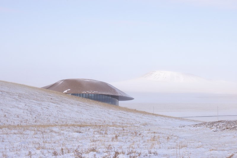 View across the steppe with the building on a low ridge and the volcano cone in the distance