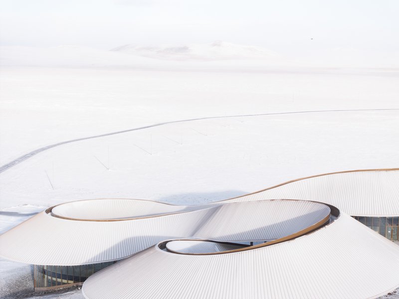 Aerial of two lobes of the roof meeting around a central skylight in heavy snow